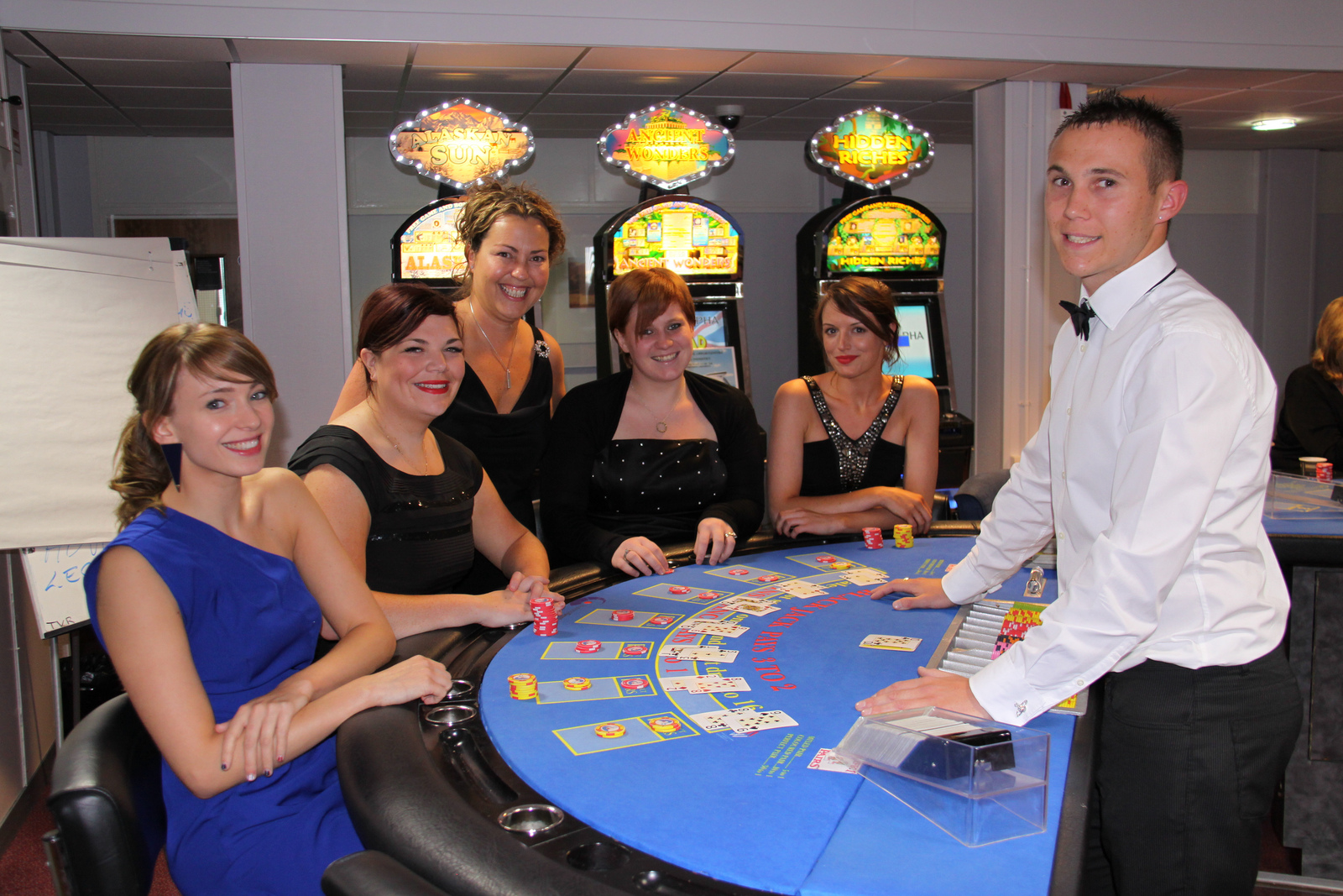 Image of a small group of people standing around the Blackjack table in B&FC Fun Casino, smiling at the camera
